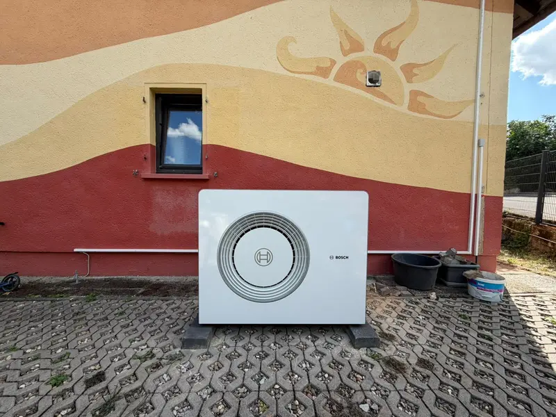 Außeneinheit einer Bosch-Wärmepumpe an einer bemalten Fassade
